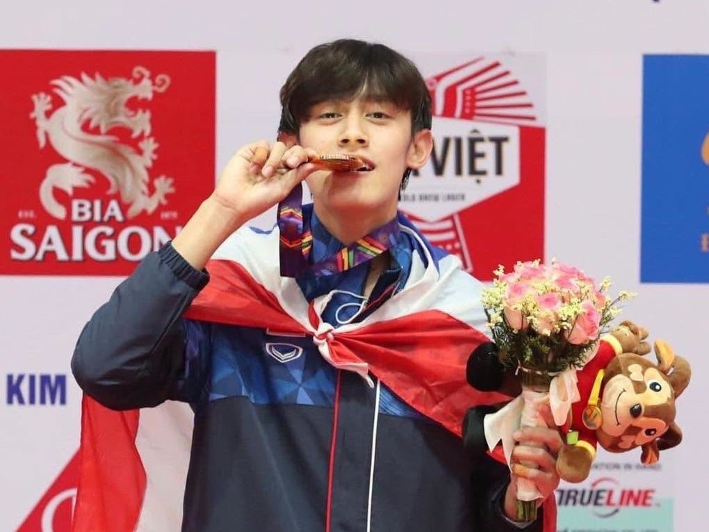 Thanakrit Yodrak biting his SEA Games 2022 men's −58 kg gold medal